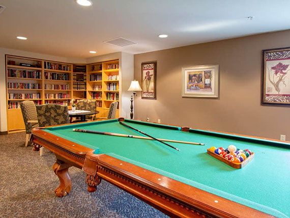 A cozy game room featuring a pool table and bookshelves filled with books.