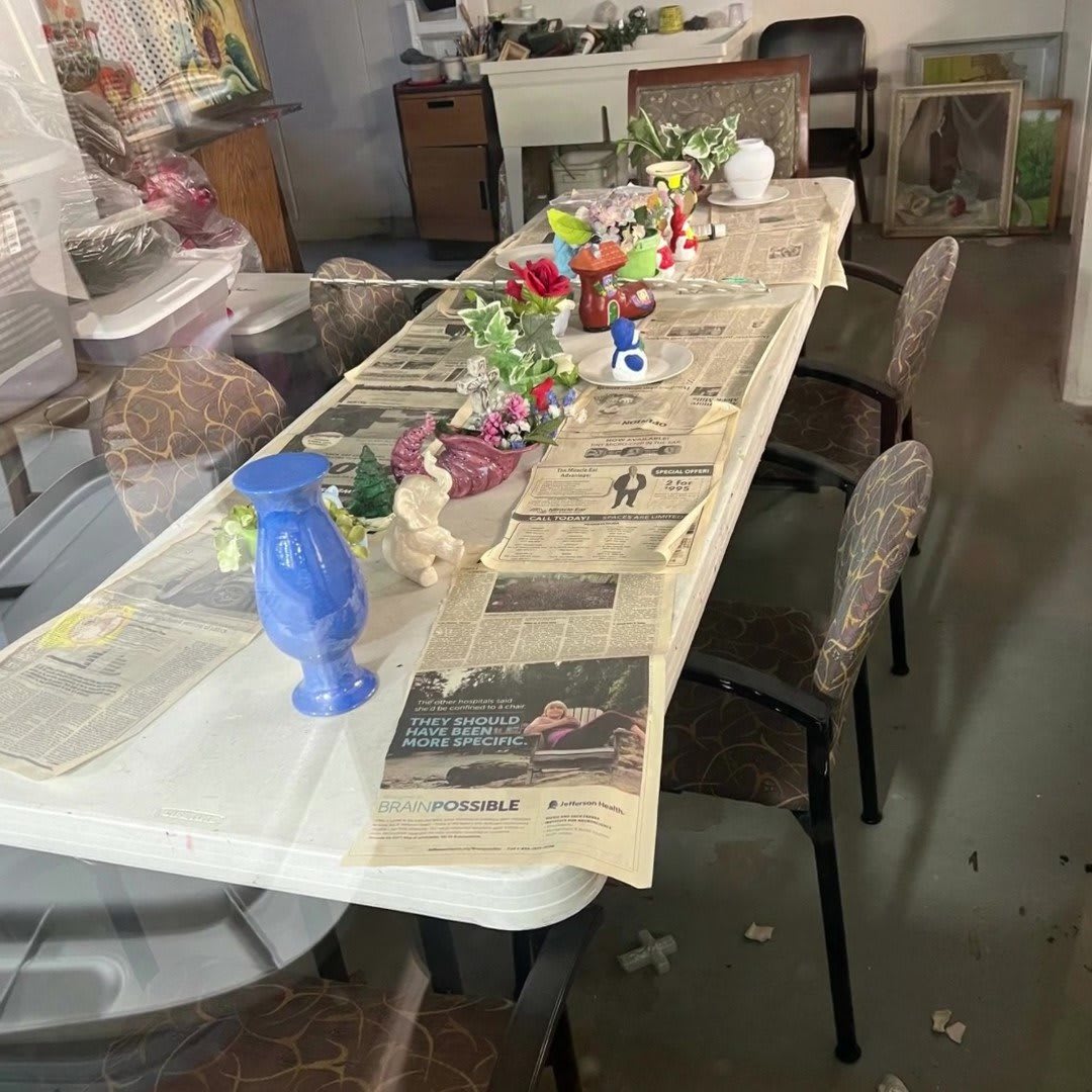 A dining table set with newspapers, vases, and flowers indoors.