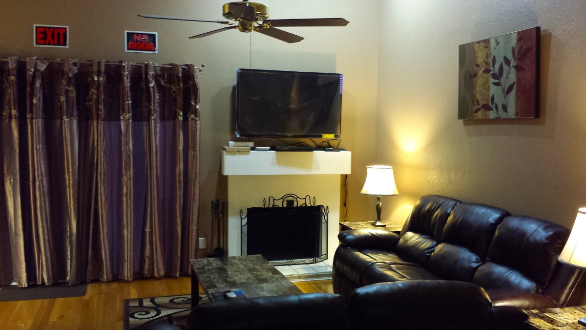 A cozy living room with a sofa, lamp, fireplace, and television.
