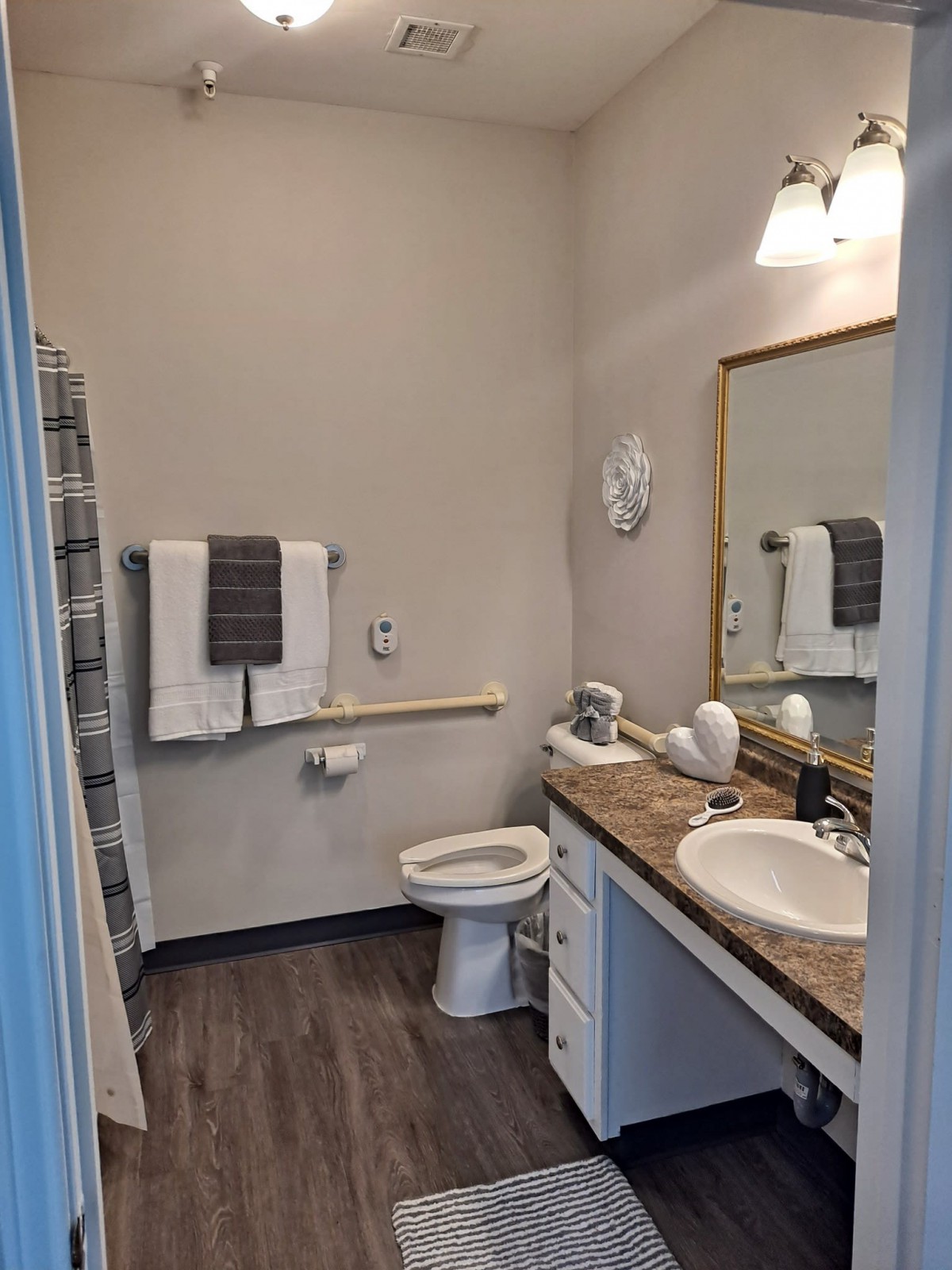 A well-lit bathroom with a toilet, sink, and towels neatly arranged.