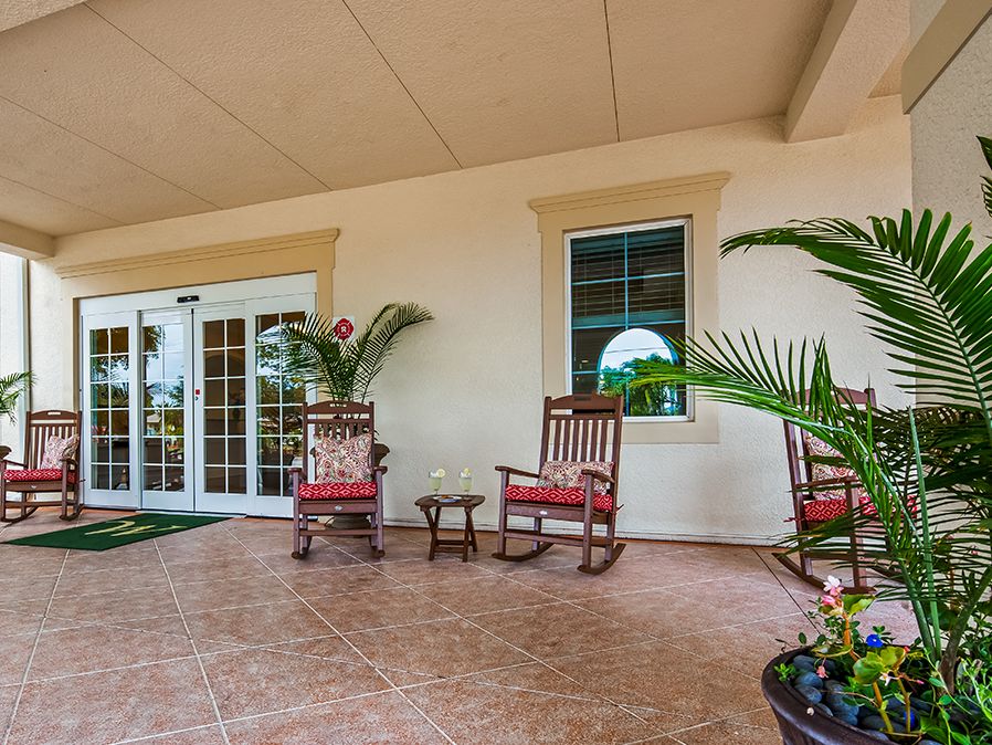 A cozy porch with rocking chairs and potted plants, featuring glass doors and windows.