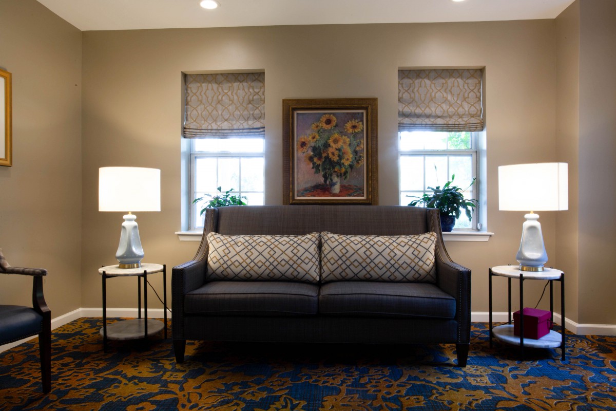A cozy living room setup with a dark sofa, side tables with lamps, and artwork above.