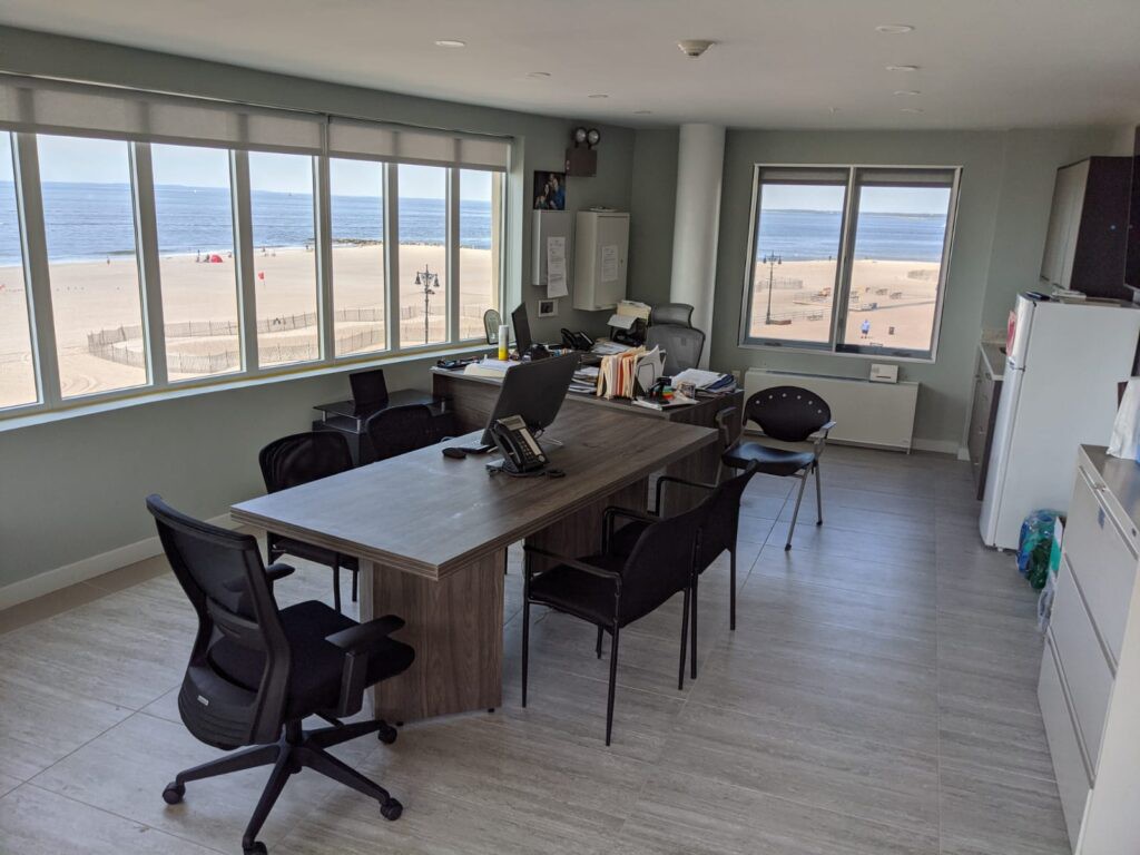 A modern office with a stunning ocean view, featuring desks and chairs.