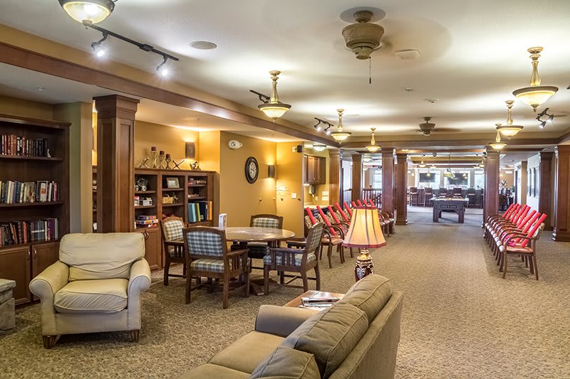 A cozy and well-lit living room area with comfortable seating and a bookshelf.