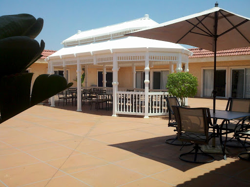 A serene outdoor space featuring a white gazebo and comfortable seating under umbrellas.