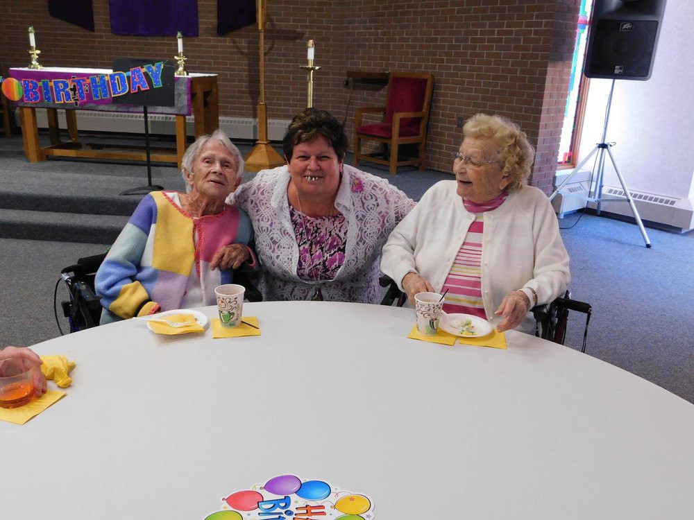 A group of three women enjoying a celebration at a community event.