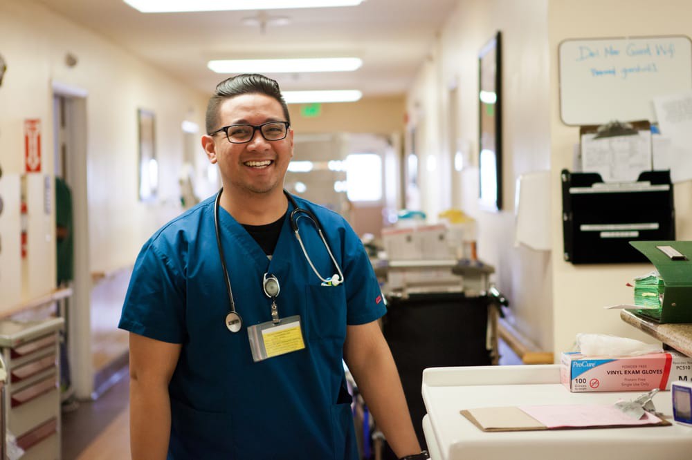A smiling nurse standing in a hospital corridor.