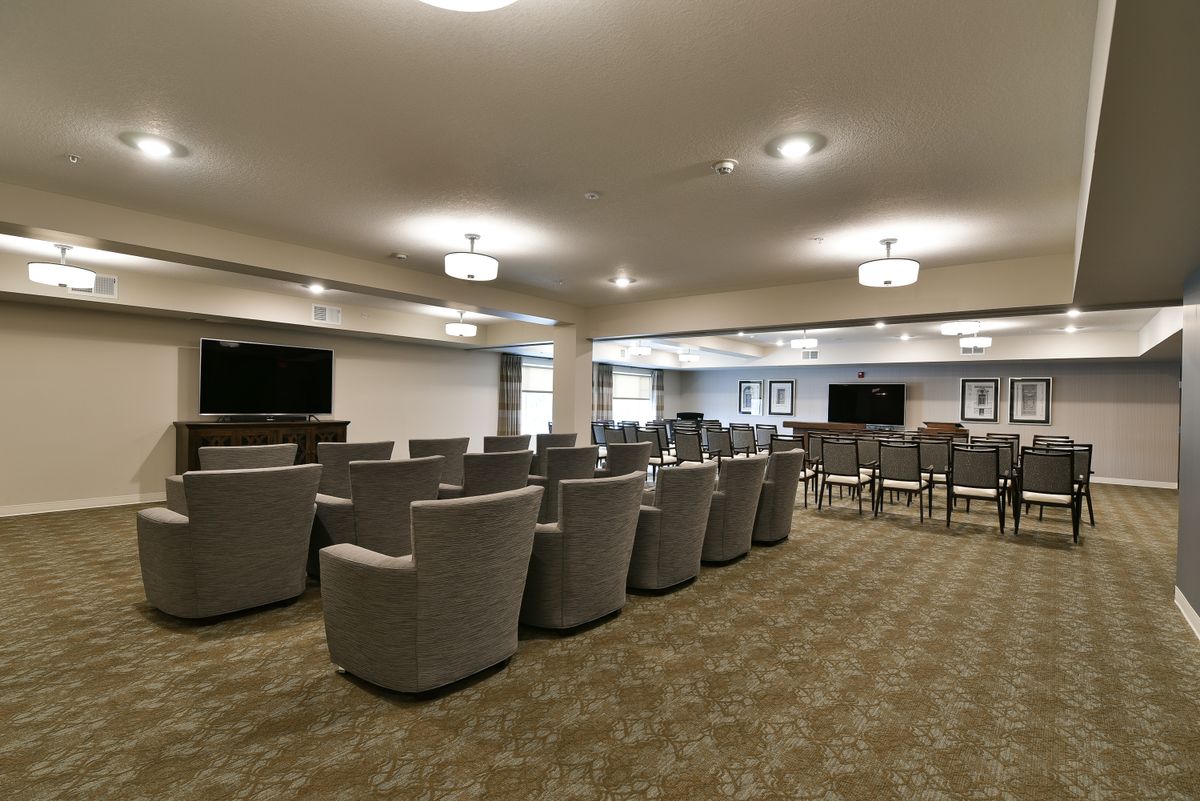 A modern conference room with rows of chairs facing multiple large televisions.
