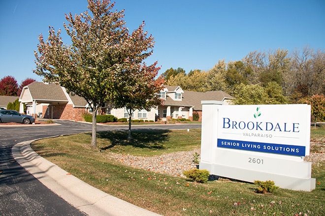 Entrance to a residential facility with a sign and fall foliage.