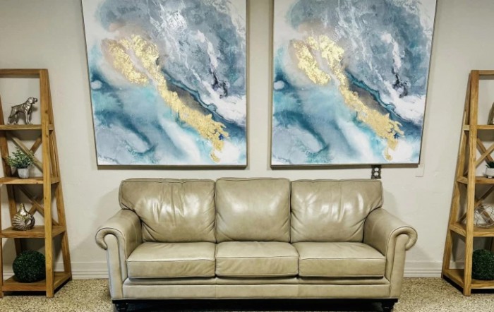 A cozy beige leather sofa placed beneath two abstract paintings in a living room setting.