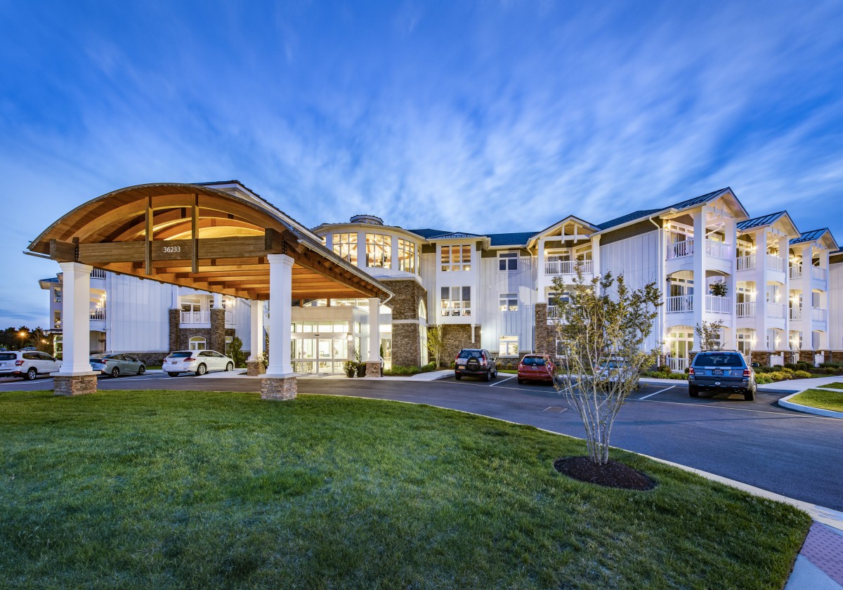 A modern hotel building with a well-lit entrance and landscaped surroundings during the evening.