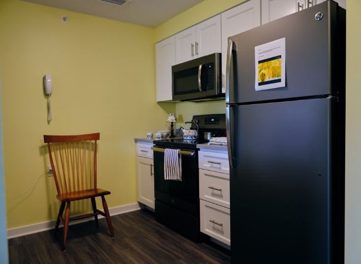 A modern kitchen with a black refrigerator, stove, microwave, and white cabinets.