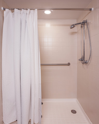 A clean and minimalist shower area featuring a white curtain and supportive grab bar.