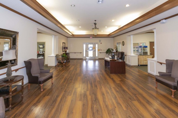A spacious lobby area with wooden flooring, featuring a reception desk and comfortable seating.