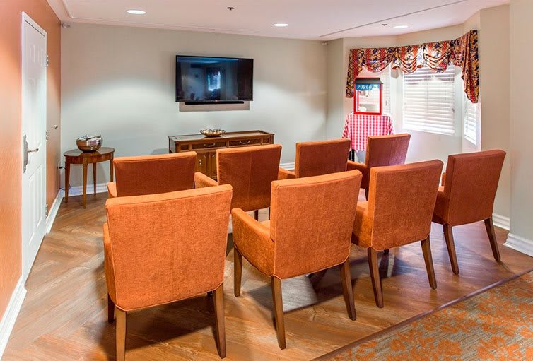 A small meeting room with rows of orange chairs facing a television.