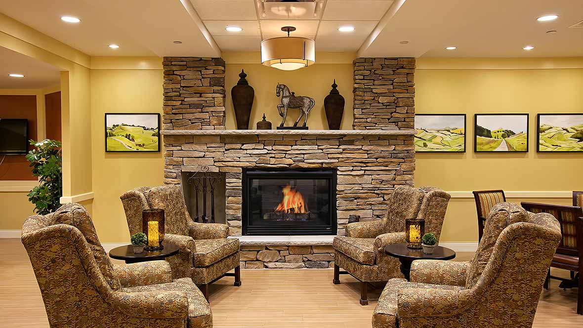 A cozy living room with a stone fireplace, warm lighting, and comfortable armchairs.