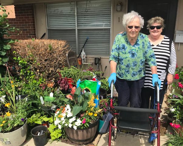 Two women enjoying a day of gardening with various plants and flowers.