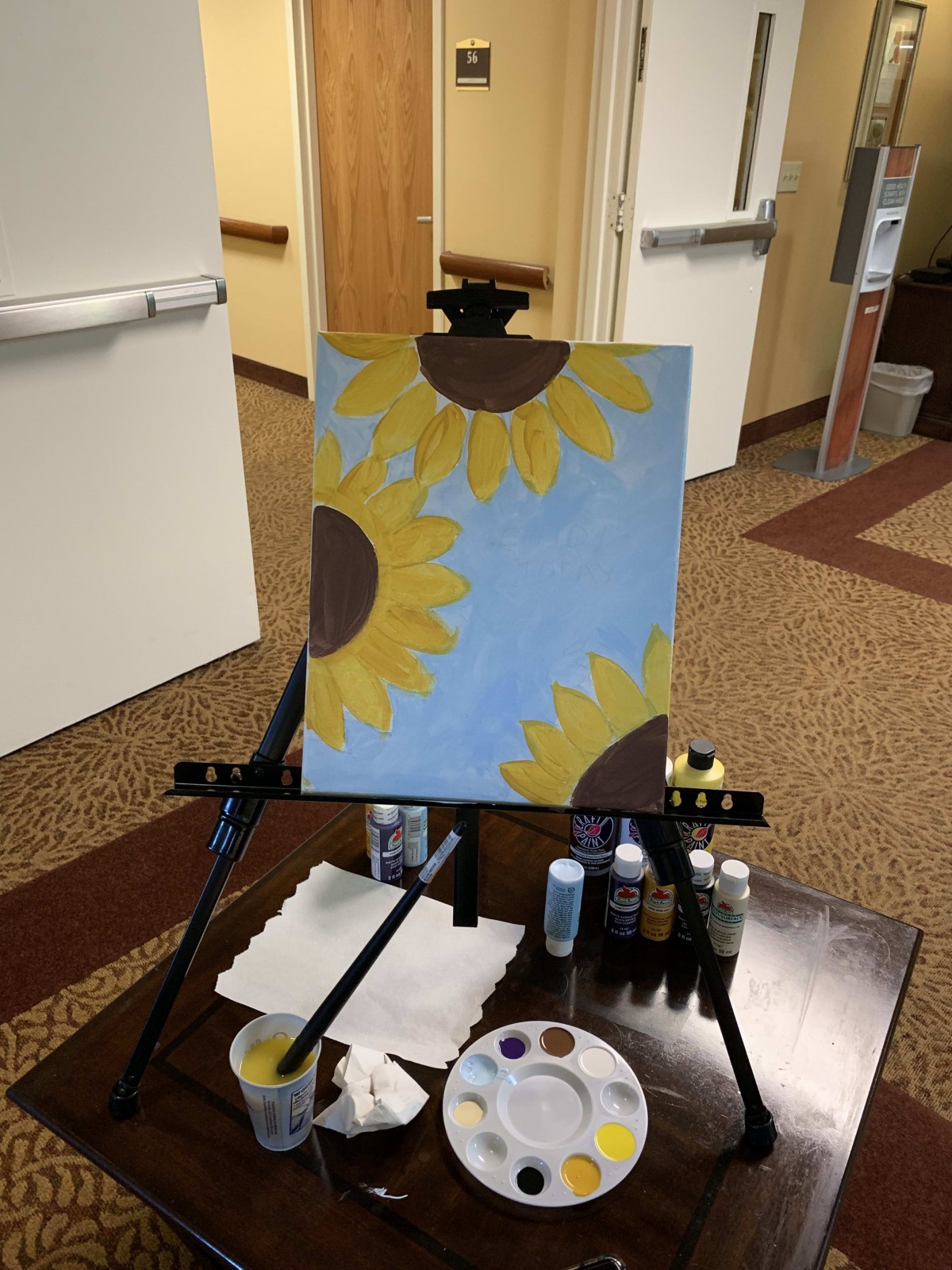 A colorful painting of sunflowers on an easel, surrounded by art supplies.