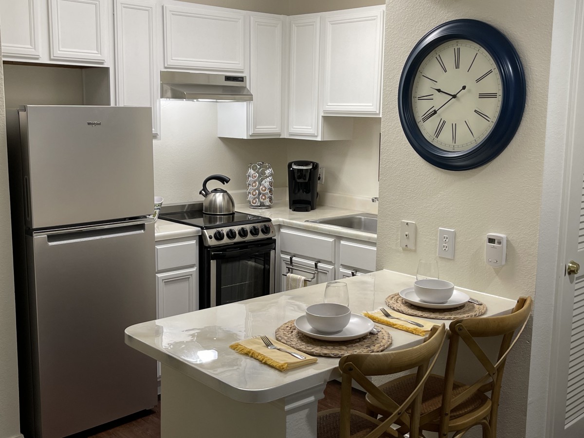 A compact apartment kitchen with a dining counter set for two.