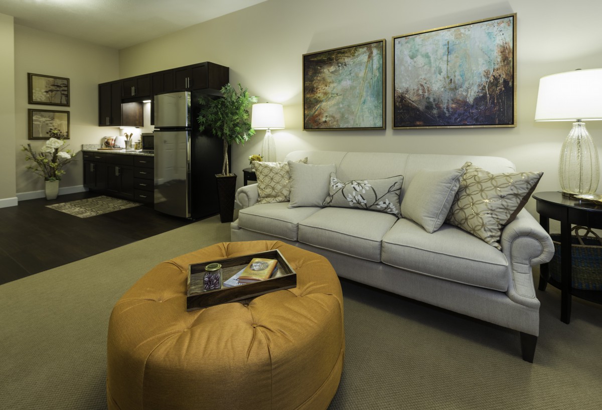 A modern living room with a comfortable sofa, stylish artwork, and a cozy ottoman.