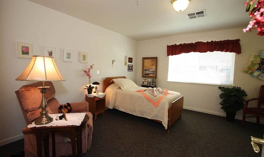A cozy bedroom with a single bed, adorned with simple decor and illuminated by natural light from a window.