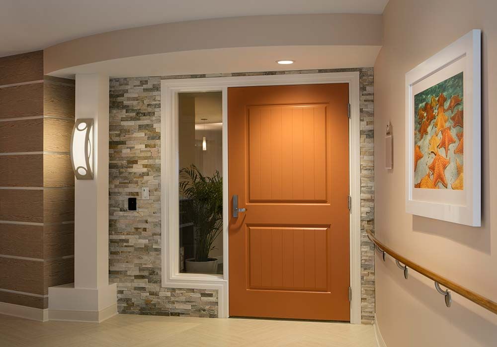 A modern interior entrance featuring a wooden door, stone wall accents, and a light fixture.