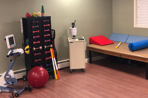 A well-equipped therapy room featuring various exercise tools and a bench for rehabilitation.