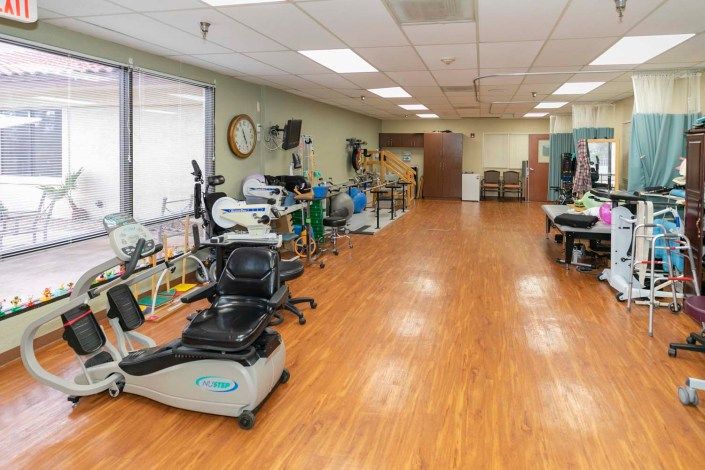 A physical therapy room equipped with various exercise machines and rehabilitation equipment.