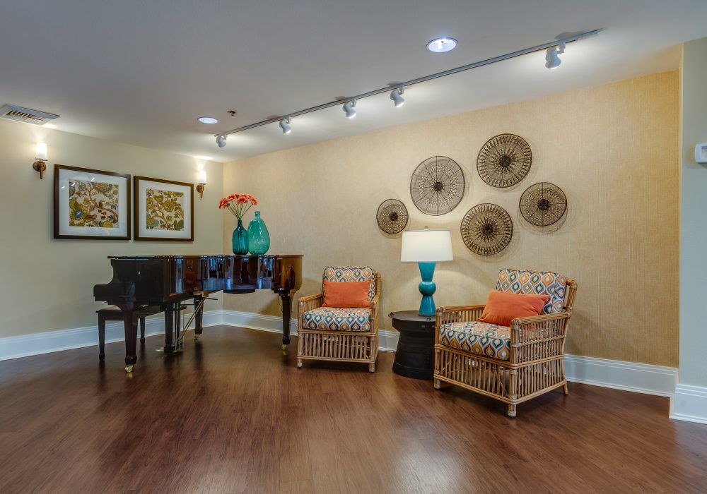 A cozy living room with rattan chairs and colorful decor, featuring a stylish arrangement of wall art and a vibrant table lamp.