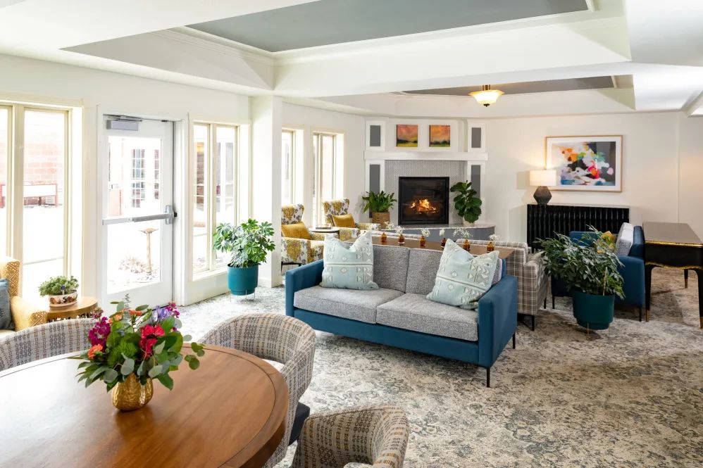 A bright and stylish living room with a blue sofa, a cozy fireplace, and modern decor.
