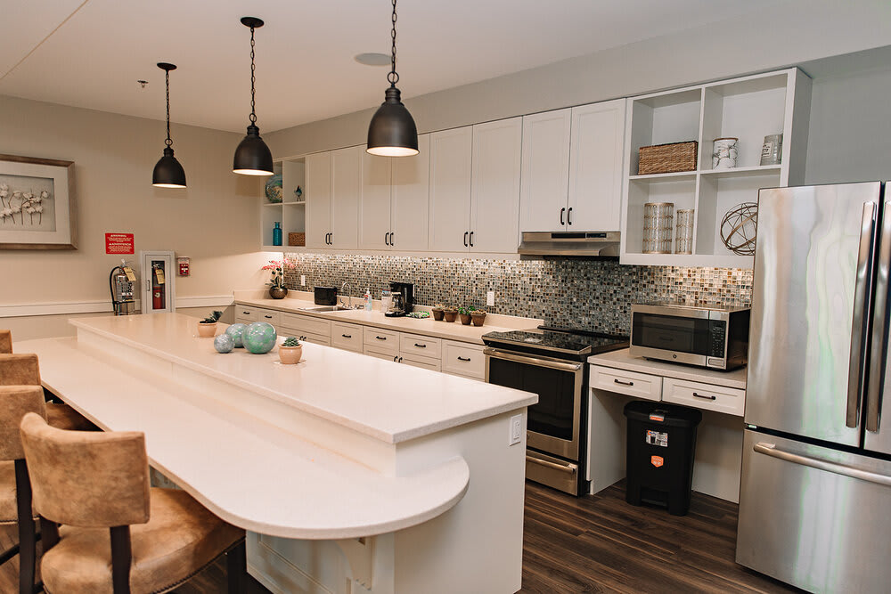 A modern kitchen with white cabinets, a central island, and stylish pendant lights.