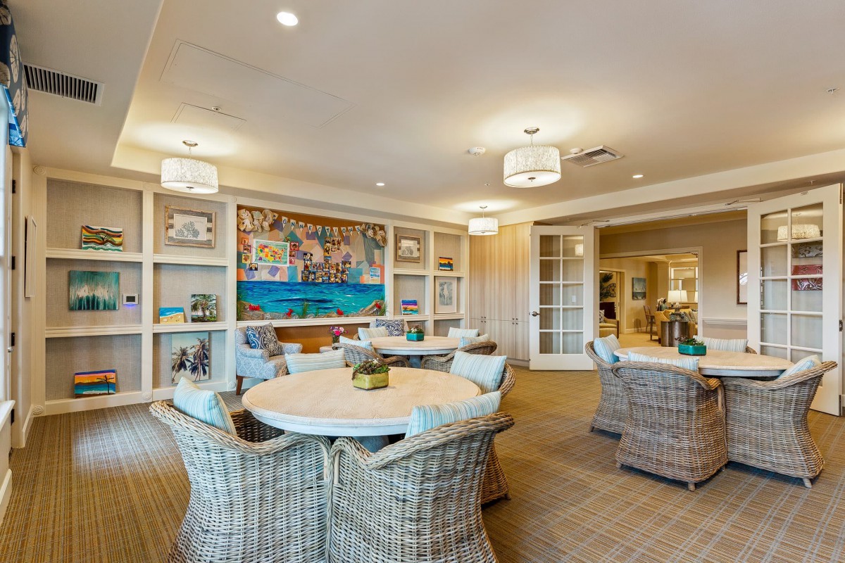 A cozy and bright lounge area with wicker furniture and decorative artwork on the walls.