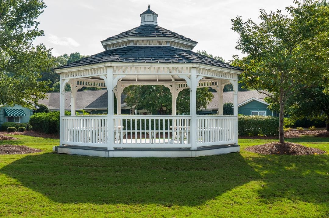 A charming white gazebo in a lush garden setting.