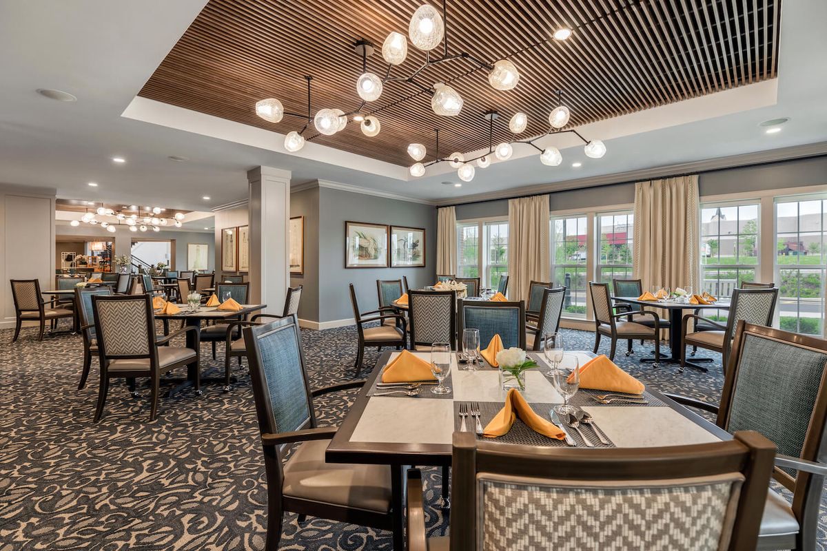 A spacious and elegantly decorated dining room with modern lighting and neatly arranged tables.