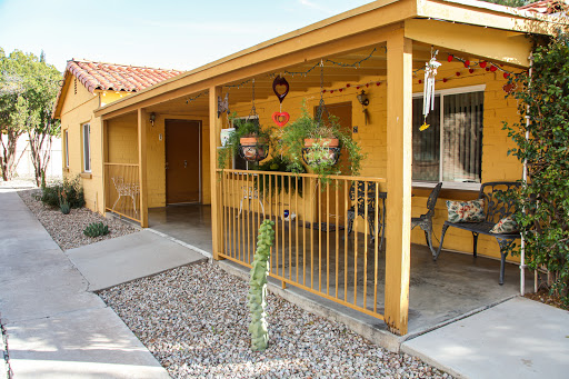 A welcoming yellow house with a charming porch adorned with plants and decorative elements.