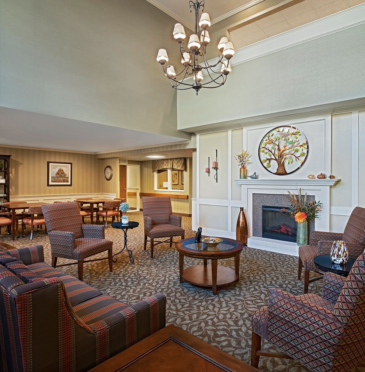 A cozy lounge area with comfortable seating, a fireplace, and a chandelier.