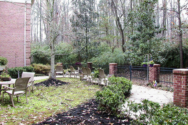 A scenic garden with a pathway lined by trees and bushes.