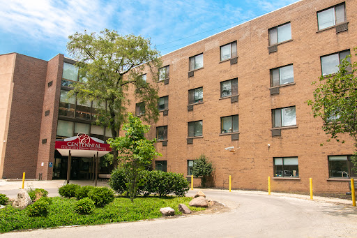 A residential brick building surrounded by greenery under a clear blue sky.