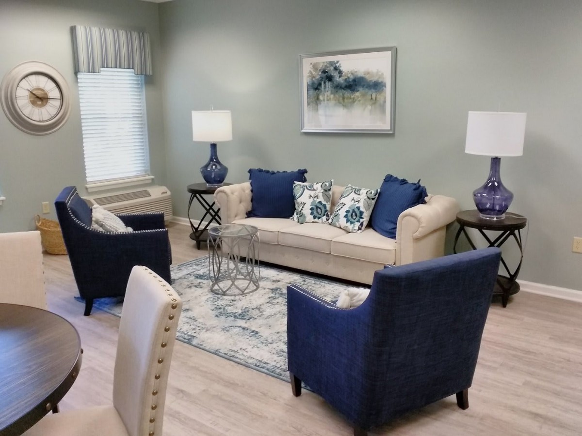 A cozy living room with a neutral-colored sofa, blue armchairs, and matching decor accents.