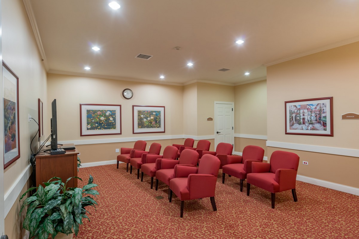 A cozy waiting room with rows of red chairs and framed artwork on the walls.