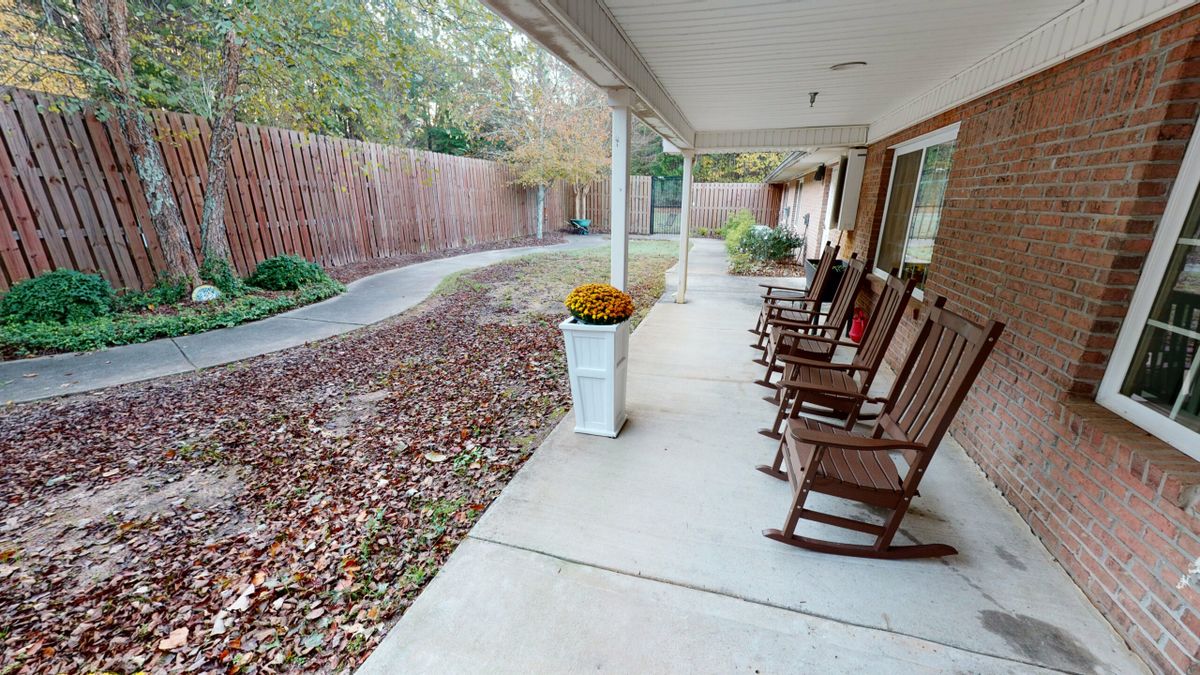 A serene patio with rocking chairs and autumn leaves scattered around.