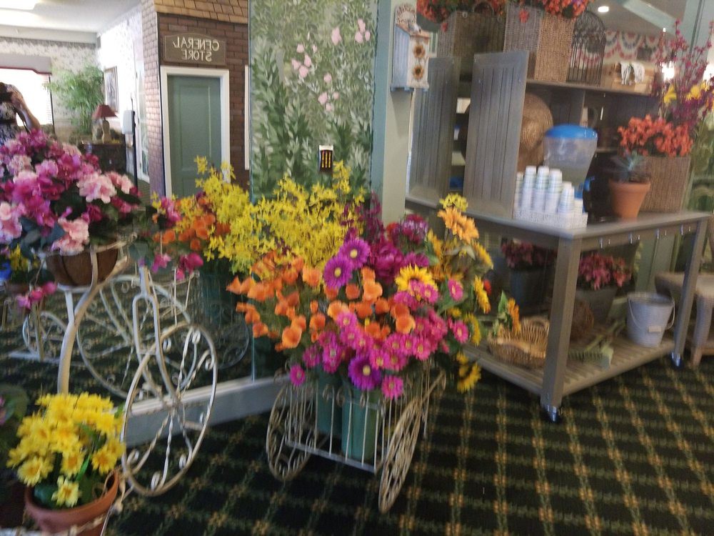 A decorative display of colorful flowers arranged in a vintage-style cart indoors.