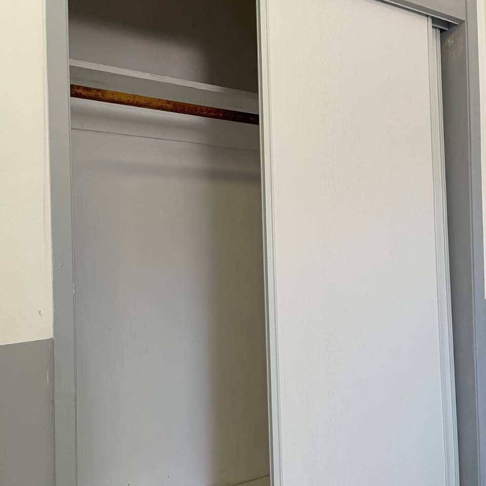 An empty closet with a sliding door and a wooden rod.