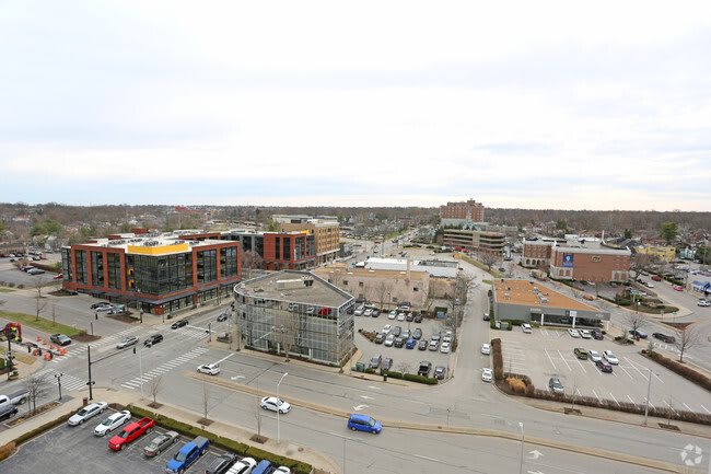 A view of an urban area with buildings, roads, and a parking lot on an overcast day.