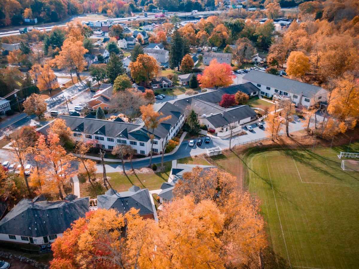 Aerial view of a suburban neighborhood showcasing vibrant autumn foliage and scattered buildings.