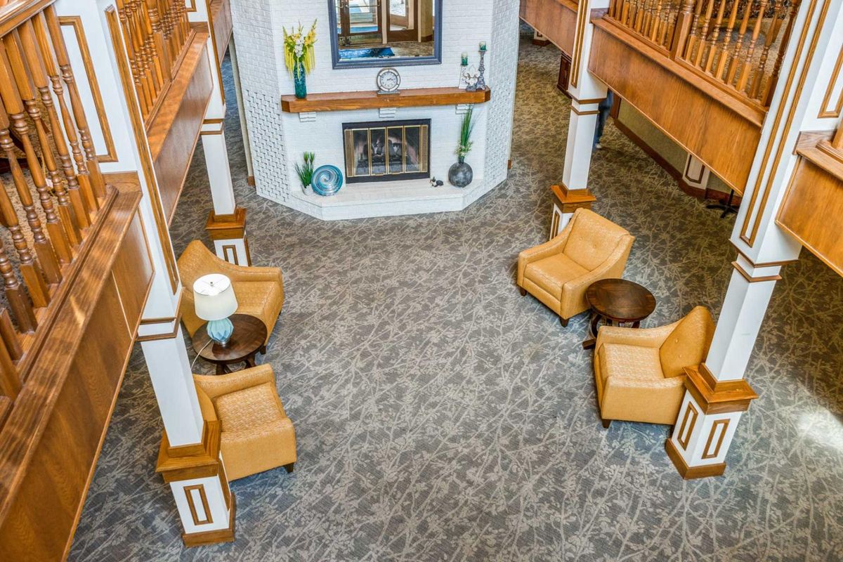 A cozy lobby seating area with upholstered chairs and a central fireplace.