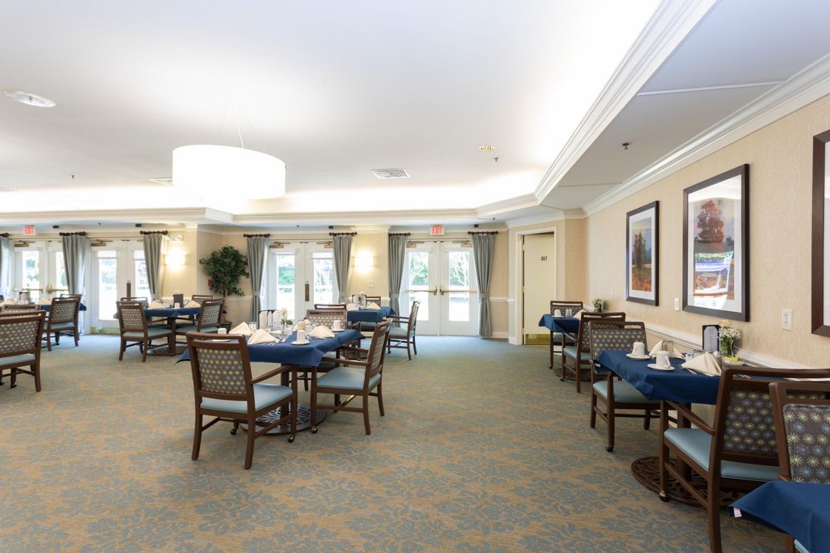 A spacious dining room with neatly arranged tables and chairs, featuring elegant lighting and decor.