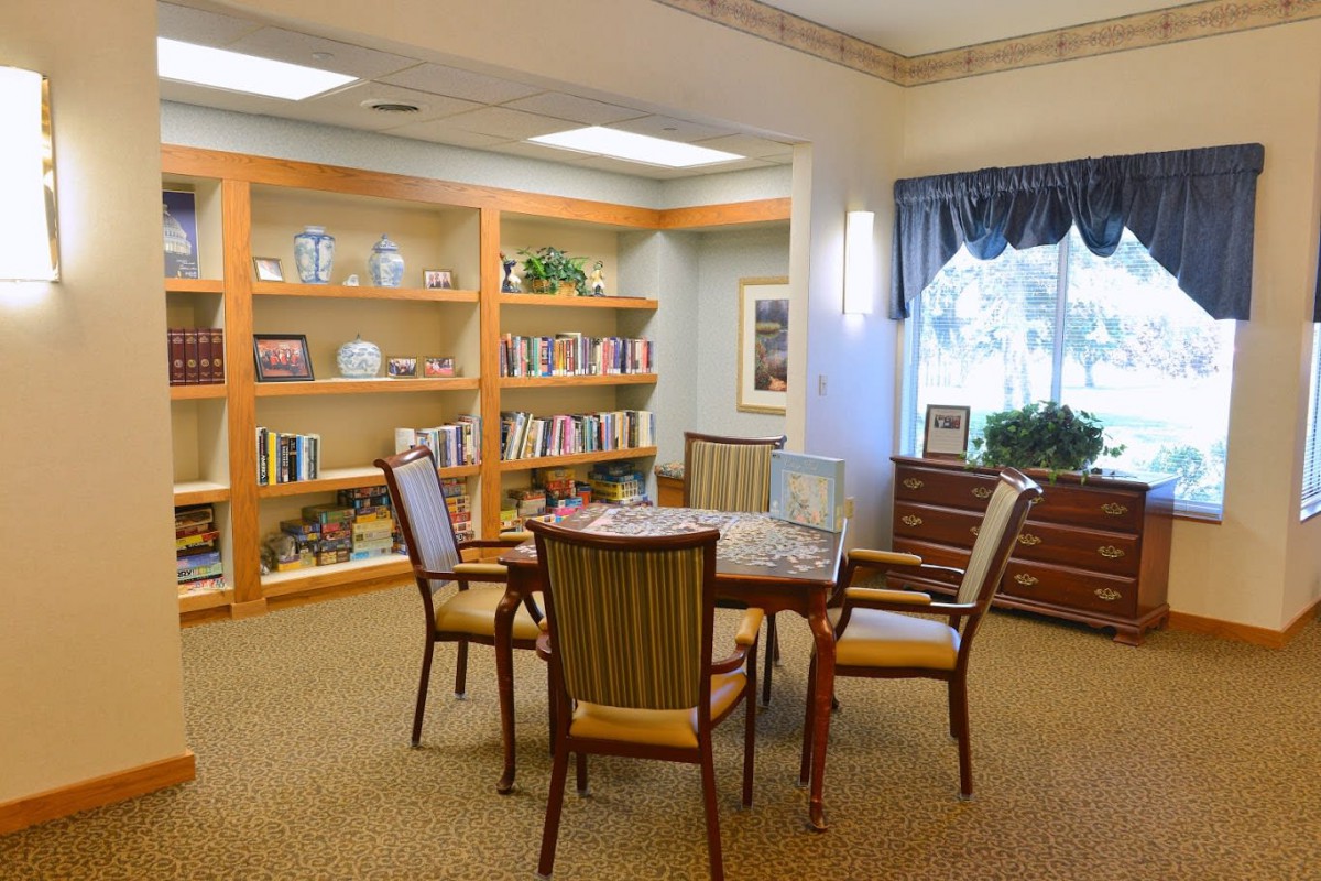 A cozy library reading room with bookshelves, a table, and chairs.