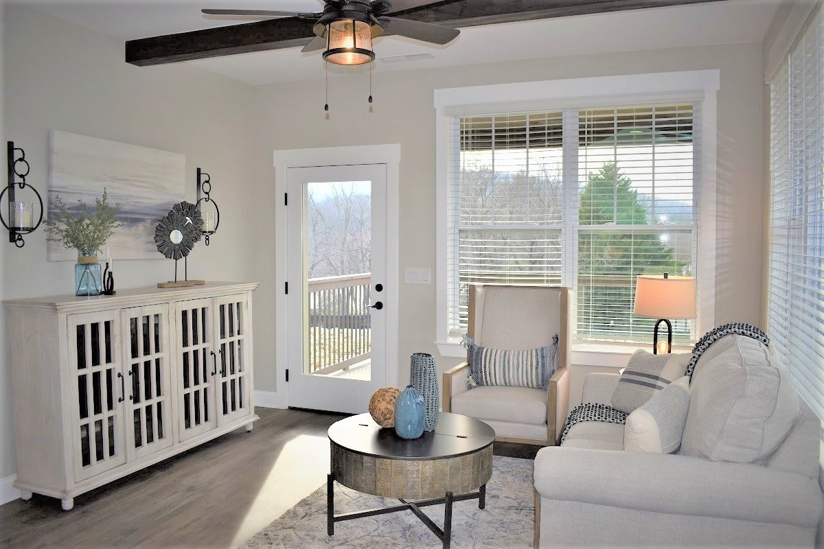 A modern living room with neutral colors, featuring comfortable furniture and ample natural light through large windows.
