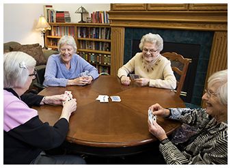 A group of elderly individuals enjoying a card game in a cozy library setting.